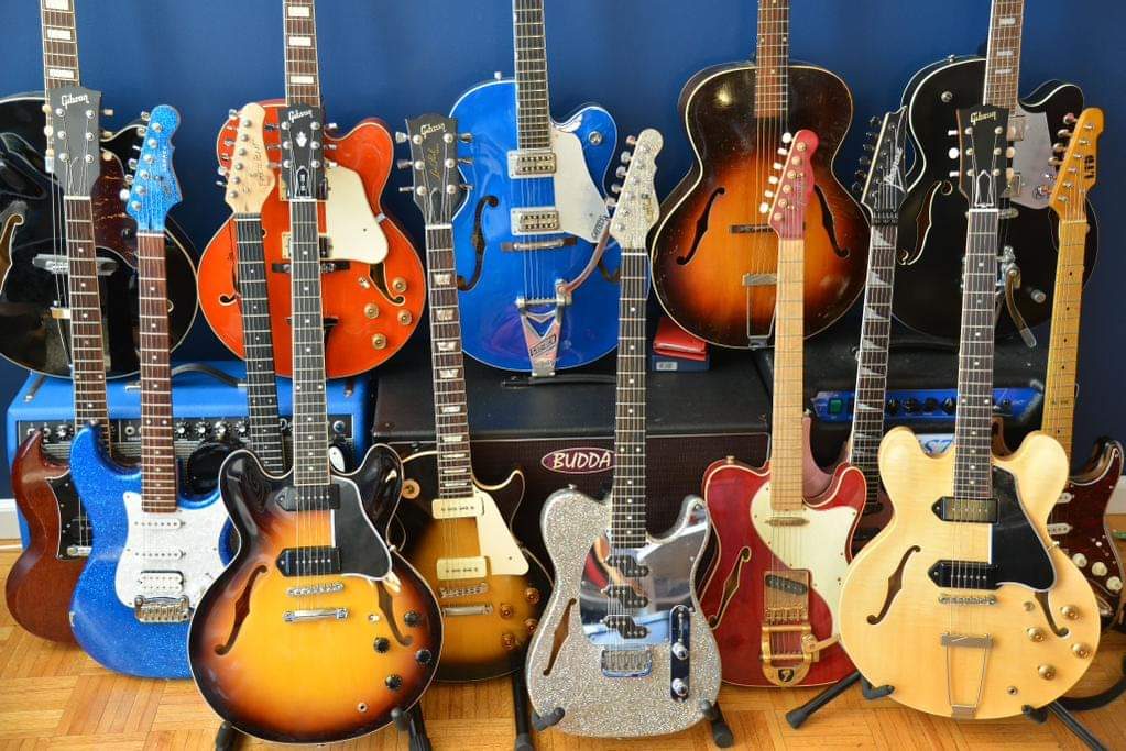 The author's guitar collection: semi-hollows, Telecasters, and archtops in front of amps